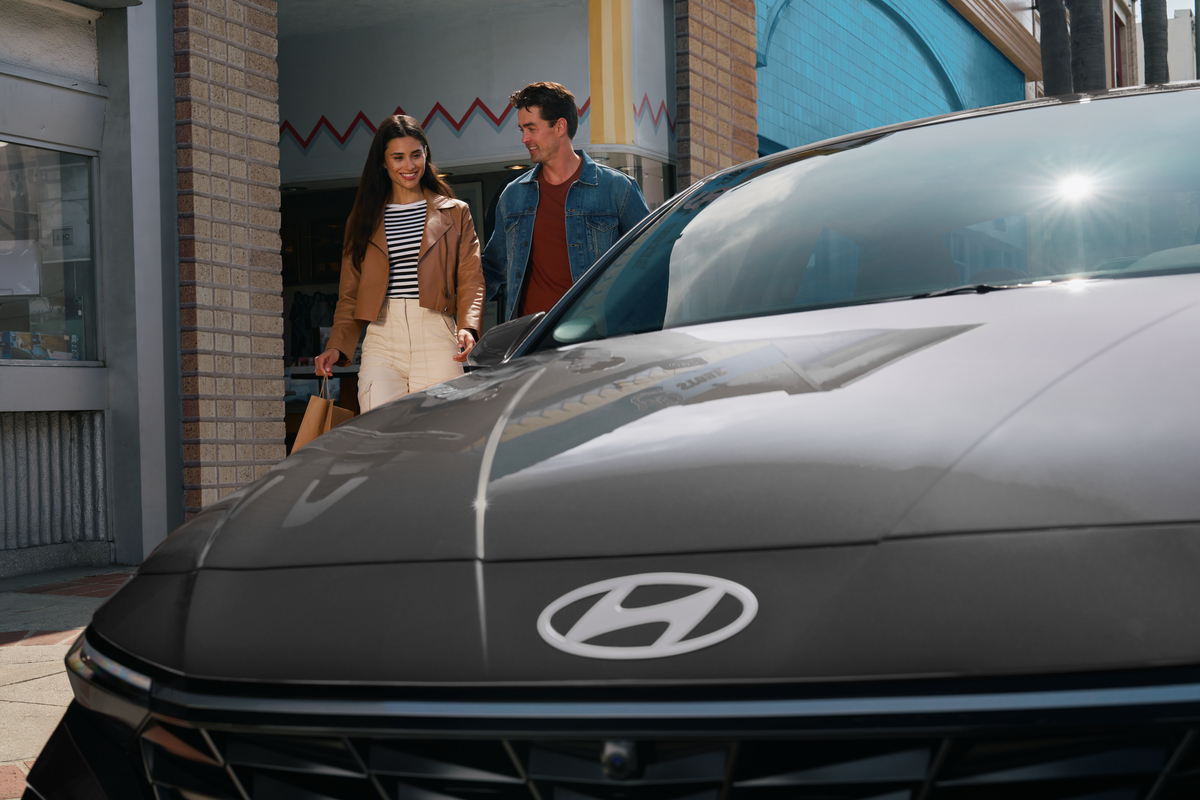 Happy couple standing near the 2026 Hyundai Elantra Hybrid